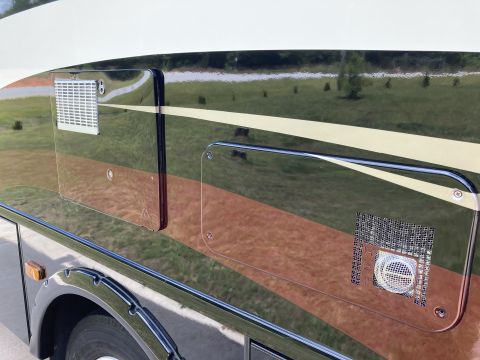 2015 Ford F-550 - Exterior view of an RV showing two access panels with vents and reflective striping.