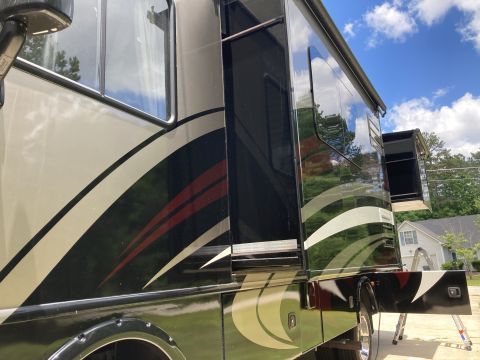 2015 Ford F-550 - Side view of a motorhome with a graphic design and an extended awning.