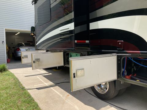2015 Ford F-550 - Side view of an RV with storage bays open, revealing a generator and plumbing systems.