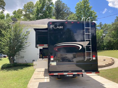 2015 Ford F-550 - Rear view of a dark-colored RV motorhome with a ladder and slide-out extended.