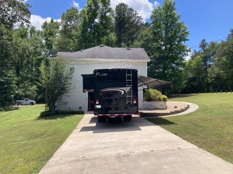 2015 Ford F-550 - Rear view of a black RV motorhome parked in a driveway, with a silver pickup truck visible in the background.