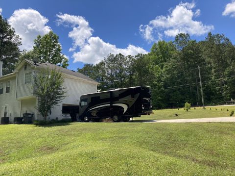 2015 Ford F-550 - A motorhome is parked on a grassy lawn next to a two-story house.