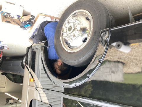 2015 Ford F-550 - A person is working inside the wheel well of a large RV.