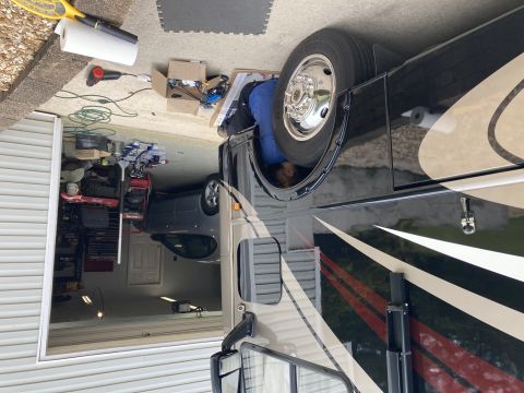 2015 Ford F-550 - A person works on the interior of a large RV motorhome parked in a garage, with another car visible behind it.