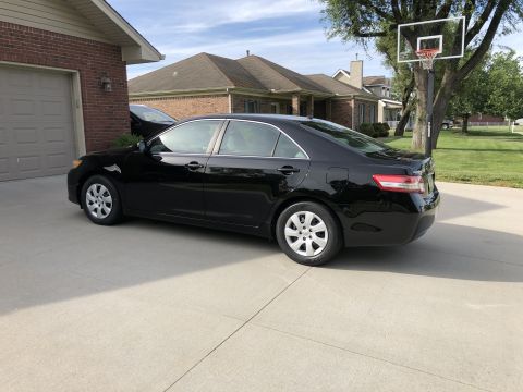 2011 Toyota Camry - A black 2011 Toyota Camry is parked in a suburban driveway on a sunny day.