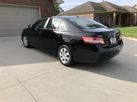 2011 Toyota Camry - A black Toyota Camry is parked in front of a brick house and garage.