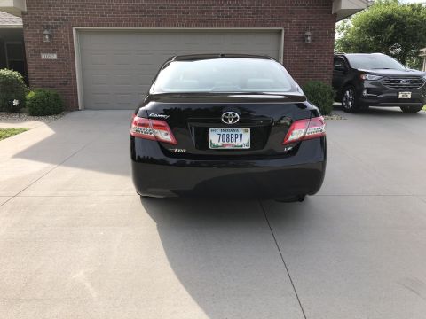 2011 Toyota Camry - Rear view of a black 2011 Toyota Camry LE. A dark SUV is visible to the right.