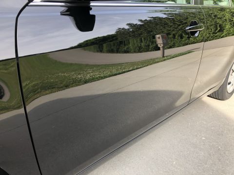 2011 Toyota Camry - The glossy finish of the car's side reflects the surrounding environment, including trees and a paved surface.