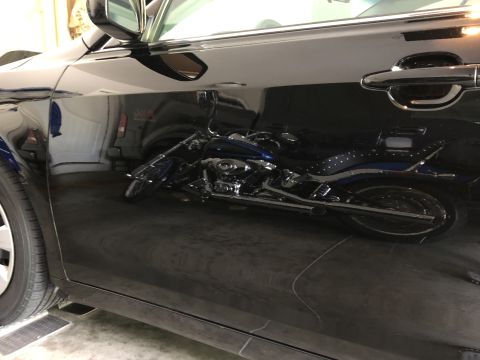 2011 Toyota Camry - Reflection of a blue motorcycle on the side of a black car.
