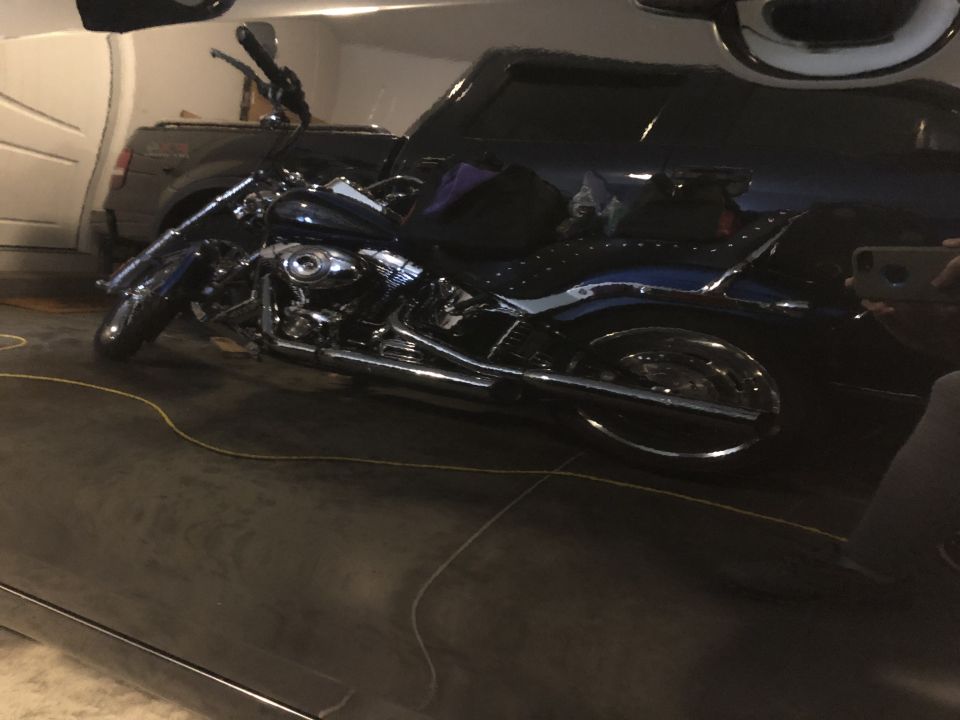 Dark blue motorcycle parked in front of a dark SUV in a garage
