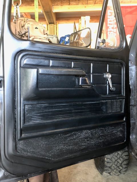 1978 Ford Bronco - The interior door panel of a 1978 Ford Bronco shows its manual window crank and textured armrest.