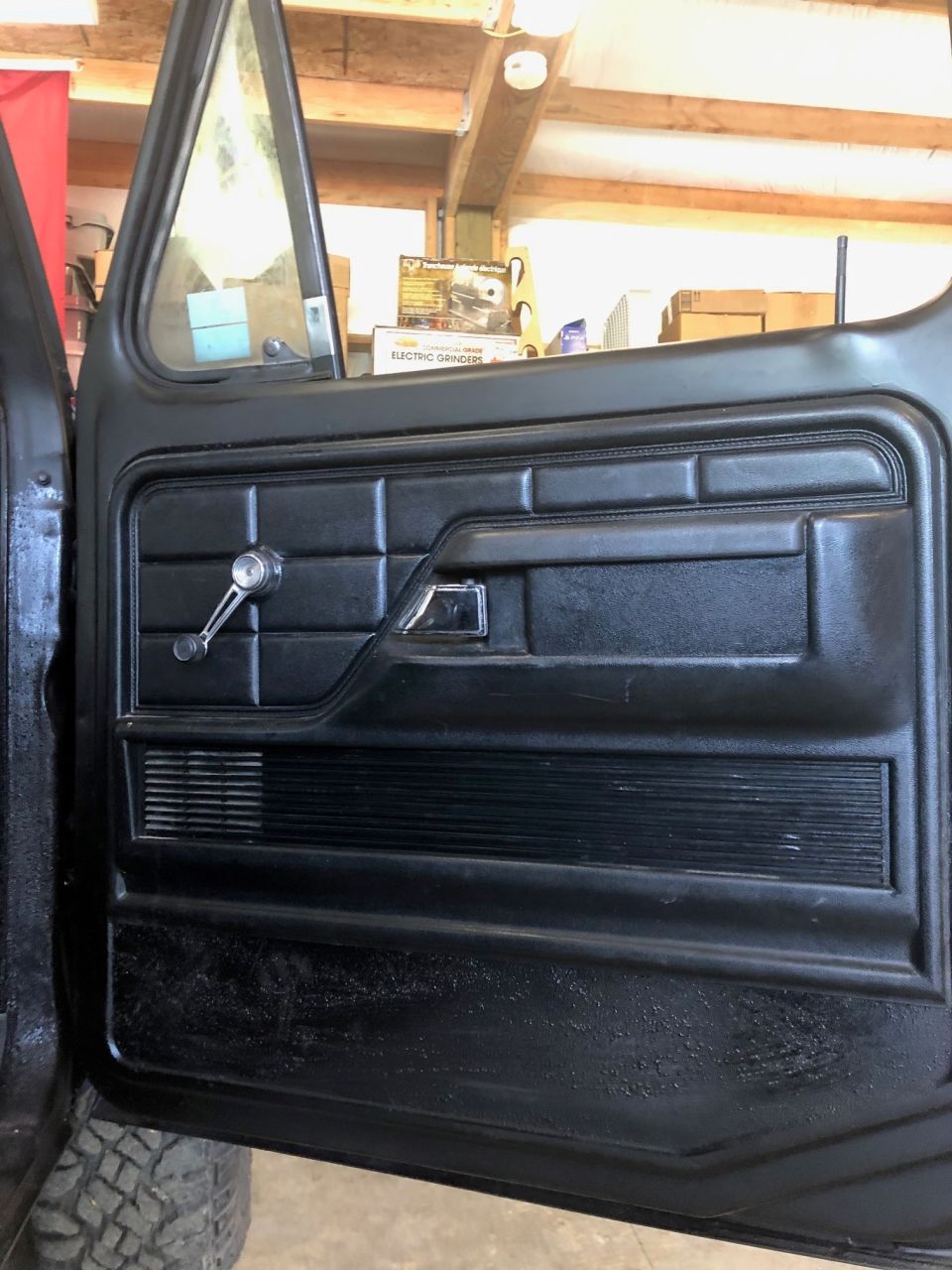 Black interior door panel with chrome window crank and door handle