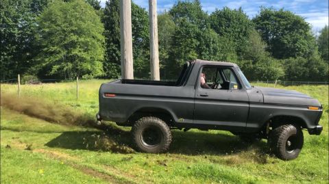 1978 Ford Bronco - A 1978 Ford Bronco is shown from the side as it drives off-road, emitting dark smoke.