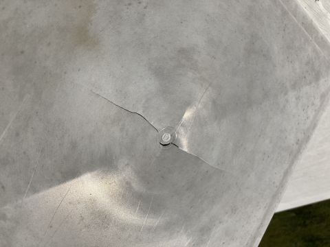 2015 Ford F-550 - A close-up view of a damaged metal surface with a visible crack and a rivet holding it together.