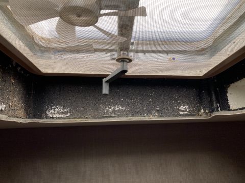 2015 Ford F-550 - Interior view of a RV roof vent with a manual crank mechanism visible. The vent screen is dusty and the surrounding seal appears to be dete…