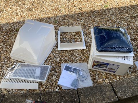 2015 Ford F-550 - A collection of RV roof vent parts, including a white outer cover, a white frame, a dark tinted inner lid still in plastic wrap, a white gr…