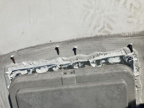 2015 Ford F-550 - Several screws are visible securing a gray plastic vent cover to a white surface. White sealant is applied around the edge of the vent cove…