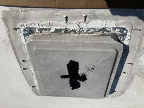 2015 Ford F-550 - A close-up view shows a gray plastic vent cover secured to a white surface with multiple screws and sealant. Black sealant is applied in a…