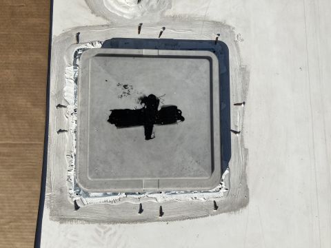 2015 Ford F-550 - A square roof vent is sealed with black sealant and screws on a white RV roof. The sealant is applied in a cross shape over the vent openin…