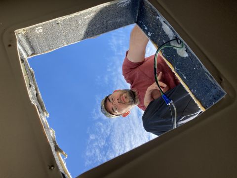 2015 Ford F-550 - A person looks down through a square opening in a vehicle's ceiling, with wires visible near the opening's edge. The opening reveals a brig…