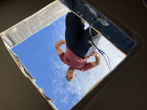 2015 Ford F-550 - A man is looking down through a square opening in a structure. The sky is visible through the opening.