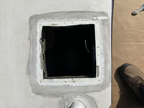 2015 Ford F-550 - A square opening in a white roof surface is sealed with gray sealant around its perimeter. A green wire is visible inside the opening, and…