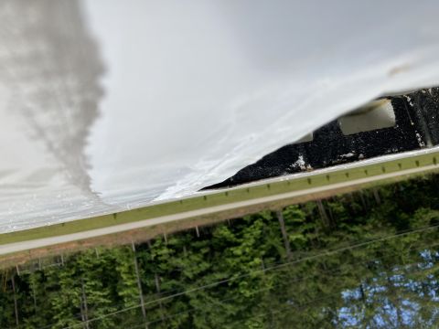 2015 Ford F-550 - A close-up, low-angle shot shows the underside of a white vehicle panel peeling away from a black textured surface, revealing a glimpse of…