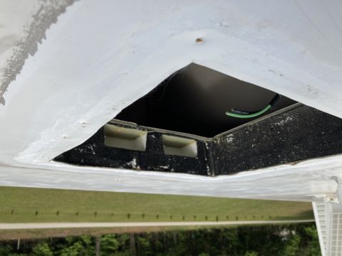 2015 Ford F-550 - A close-up view of a white RV roof with a square opening revealing black insulation and exposed green and black wires. The opening is seale…