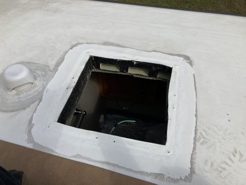 2015 Ford F-550 - A white RV roof with a newly sealed skylight opening and a vent cover. The sealant is applied around the square opening and the base of the…