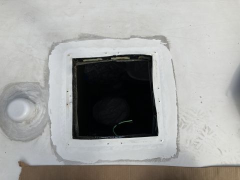 2015 Ford F-550 - A square opening has been cut into a white surface, possibly a vehicle roof or wall, with sealant applied around the edges. A white plastic…
