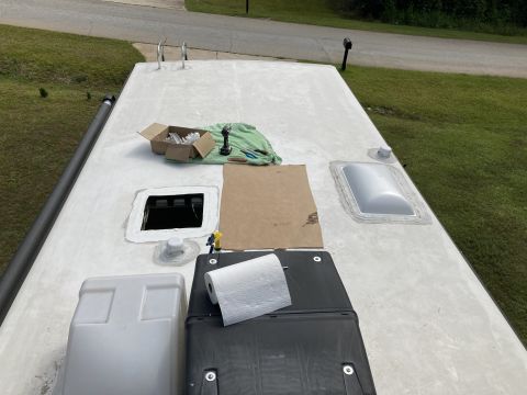 2015 Ford F-550 - The roof of an RV is shown with various components and tools for maintenance. Visible items include a skylight, vents, a paper towel roll,…