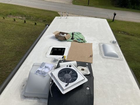 2015 Ford F-550 - The roof of an RV is shown with various components and tools laid out for repair or installation. Visible items include a new fan, a skylig…