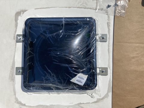 2015 Ford F-550 - A dark tinted skylight is installed on a white surface, likely a vehicle roof, with white sealant around the edges and metal brackets secur…