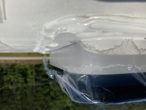 2015 Ford F-550 - A close-up, low-angle view of the underside of a white vehicle, possibly an RV or motorhome, showing a dark blue lower section covered in p…