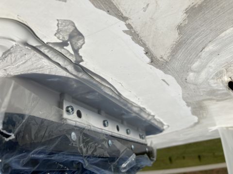 2015 Ford F-550 - A close-up, low-angle view of the underside of a vehicle, showing a white surface with grey repair patches and a metal bracket with screws…