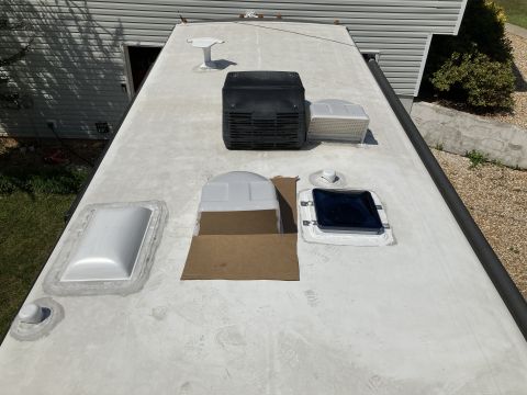 2015 Ford F-550 - A high-angle view of a white RV roof showing several fixtures including an air conditioner unit, a skylight, and a vent. The RV is parked n…