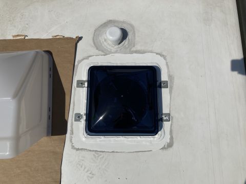 2015 Ford F-550 - A newly installed dark tinted roof vent with white sealant is shown on a white RV roof. A white RV roof vent cover is partially visible on…