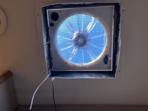 2015 Ford F-550 - A white ceiling vent fan with a blue fan is installed in the ceiling of an RV. Two wires, one white and one black, are visible hanging from…