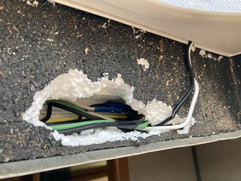 2015 Ford F-550 - A close-up view shows electrical wires running through a hole in a dark, textured material, with white expanding foam insulation visible ar…