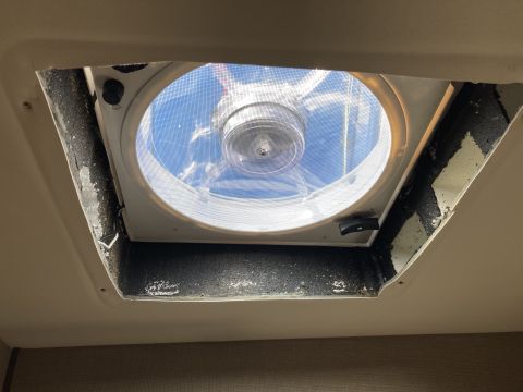 2015 Ford F-550 - A white RV roof vent fan is installed in a tan ceiling. The vent is open, revealing a screen and fan blades, with a blue sky visible throug…