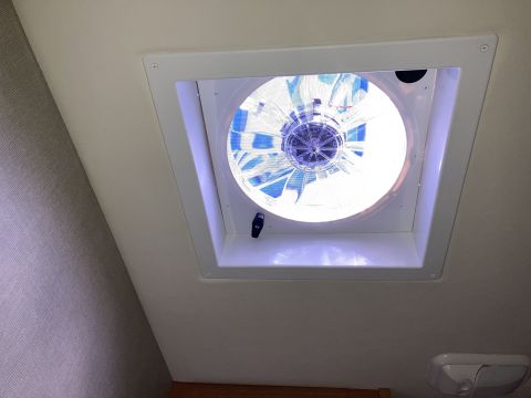 2015 Ford F-550 - A white ceiling vent fan with blue accents is installed in the ceiling of what appears to be an RV or camper. The fan is illuminated, casti…