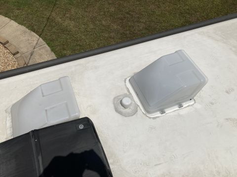 2015 Ford F-550 - A close-up view of the roof of an RV shows two white vent covers and a black folded-down awning. The RV roof is white and appears to be mad…
