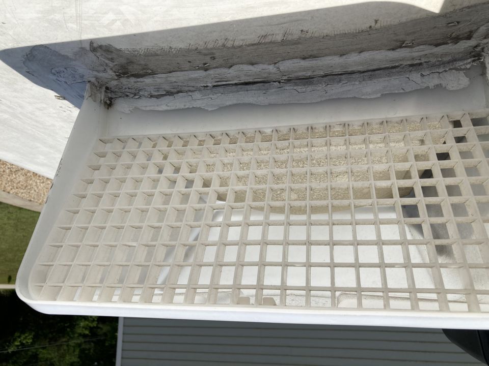 Close-up of a dusty white plastic vent with a grid pattern.