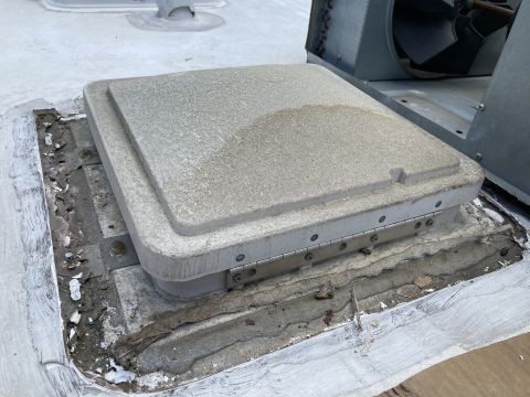 2015 Ford F-550 - A close-up view of a roof vent cover with a hinged lid, showing signs of wear and tear around the sealant.