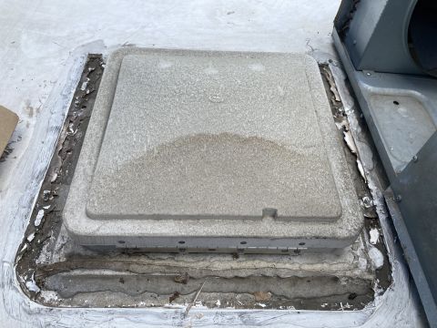 2015 Ford F-550 - A close-up view of a weathered, square vent cover on a vehicle roof, with surrounding sealant showing signs of wear and peeling.
