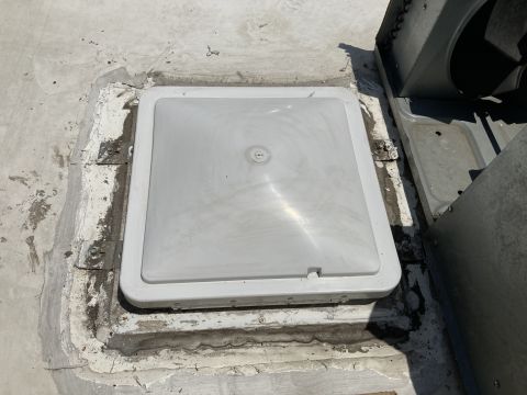 2015 Ford F-550 - A white plastic vent cover is installed on a flat roof surface. The vent cover is square with rounded corners and has a slightly domed lid.