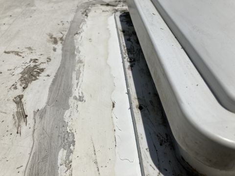 2015 Ford F-550 - A close-up view of a white RV roof shows sealant and repair work around a roof-mounted fixture. The sealant appears to be applied unevenly…