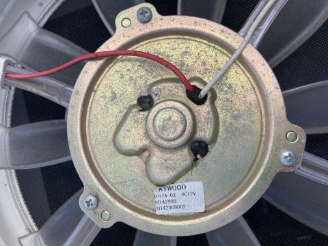 2015 Ford F-550 - A close-up view of the motor and fan blades of an Atwood 3017A-03 DC12V fan, with red and white wires connected.