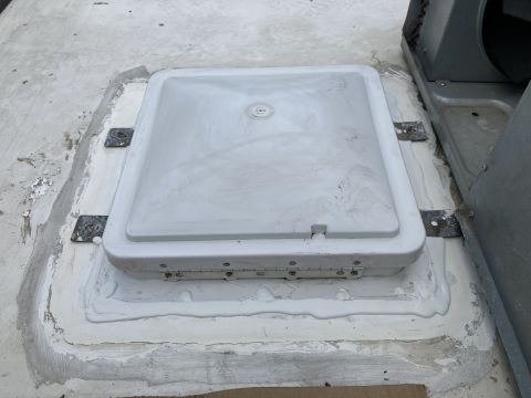 2015 Ford F-550 - A white RV roof vent with a hinged lid is sealed with white caulking to the roof of a vehicle. A portion of an air conditioning unit is vis…