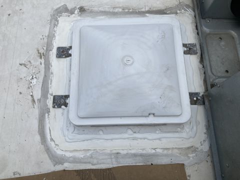 2015 Ford F-550 - A white plastic access panel is sealed with white caulk onto a white roof surface. Metal brackets with screws are visible securing the pane…